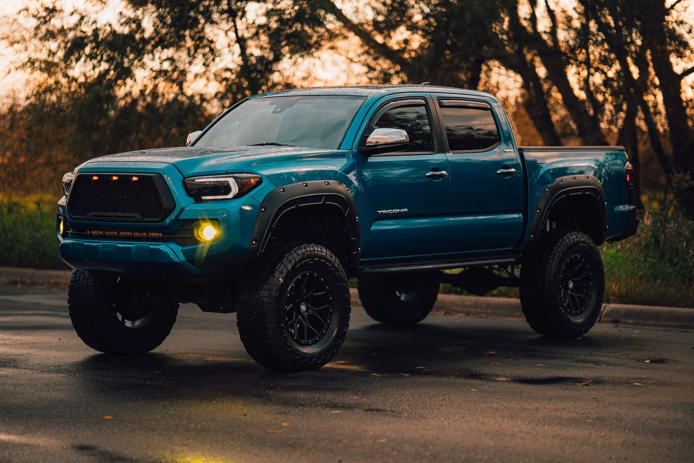 Lifted pickup truck with off-road wheels and tires at dusk